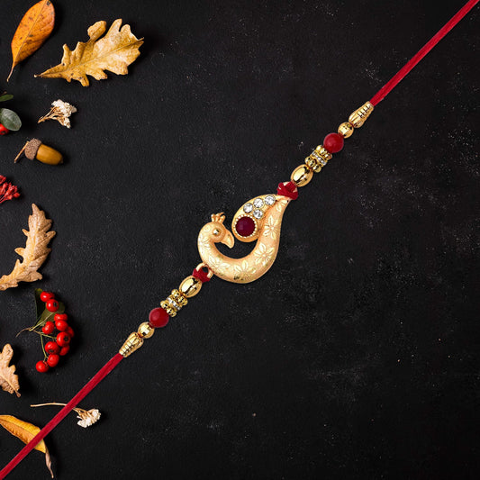 Golden Peacock Feather Rakhi With Red Thread And Kundan Detailing