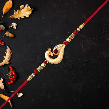 Golden Peacock Feather Rakhi With Red Thread And Kundan Detailing Wukusy