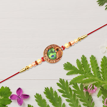 Elegant Rakhi With Peacock Feather Design And Pearl Bead Accents On Red Thread Wukusy
